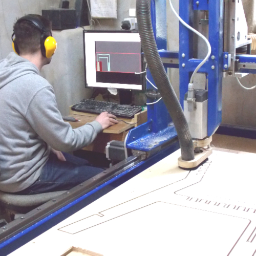A man working at a computer next to a CNC router