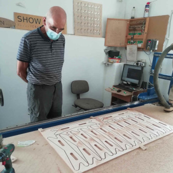 Man with a face mask looking at items cut on a CNC Router